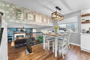 Dining room featuring dark hardwood / wood-style flooring, ceiling fan with notable chandelier, and a healthy amount of sunlight