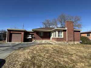 Ranch-style house with a garage, brick siding, driveway, and a front lawn