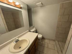 Bathroom with vanity, a tile shower, tile patterned floors, and toilet