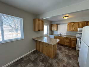 Kitchen with white appliances, kitchen peninsula, and sink