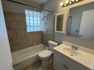 Full bathroom featuring vanity, tiled shower / bath combo, tile patterned floors, and toilet