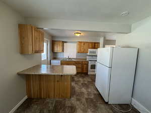 Kitchen featuring sink, white appliances, and kitchen peninsula