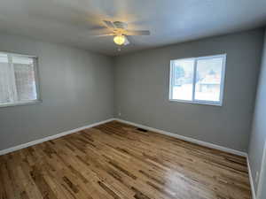 Empty room with ceiling fan and light hardwood / wood-style flooring