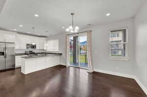 Kitchen featuring appliances with stainless steel finishes, pendant lighting, white cabinets, and kitchen peninsula