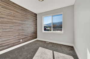 Carpeted spare room with a mountain view and wood walls