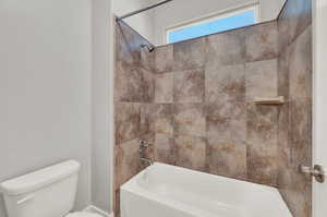 Bathroom featuring toilet and tiled shower / bath combo