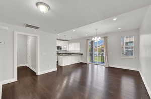 Unfurnished living room featuring dark hardwood / wood-style floors, sink, a textured ceiling, and a chandelier