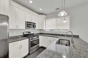 Kitchen with stainless steel appliances, sink, and white cabinets