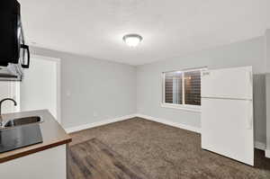 Kitchen with sink, dark colored carpet, a textured ceiling, and white refrigerator