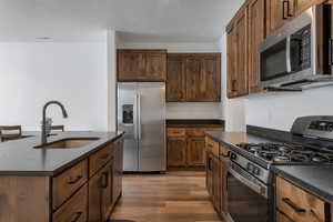 Kitchen with stainless steel appliances, hardwood / wood-style flooring, sink, and a kitchen island with sink