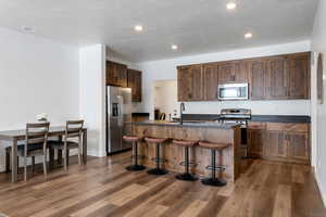 Kitchen with stainless steel appliances, sink, a center island with sink, and dark wood-type flooring