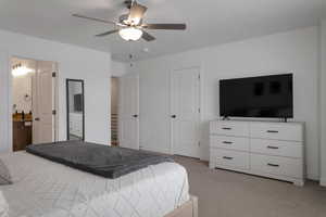 Carpeted bedroom featuring ceiling fan and ensuite bathroom