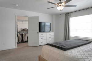 Bedroom with light colored carpet, ceiling fan, and a closet