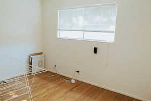 Clothes washing area with hardwood / wood-style floors and a wealth of natural light