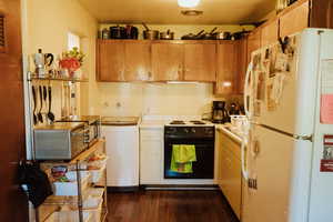 Kitchen featuring electric stove, wall oven, dark hardwood / wood-style flooring, washer / dryer, and white fridge