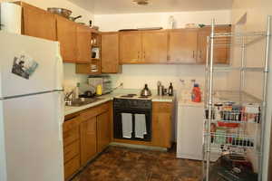 Kitchen featuring washer / dryer, sink, black electric range, white fridge, and wall oven