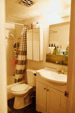 Full bathroom with toilet, vanity, shower / bathtub combination with curtain, and hardwood / wood-style flooring