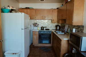 Kitchen with sink, electric range, backsplash, and white refrigerator