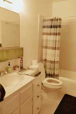 Full bathroom with vanity, shower / tub combo, tile patterned floors, and toilet