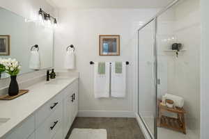 Bathroom featuring a shower with door, vanity, and tile patterned flooring