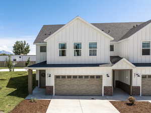 Modern farmhouse style home featuring a garage and a front lawn