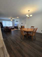 Dining space with ceiling fan with notable chandelier and dark hardwood / wood-style floors