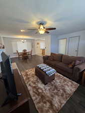 Living room featuring dark hardwood / wood-style flooring and ceiling fan with notable chandelier