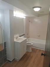 Bathroom with wood finished floors, toilet, tub / shower combination, and vanity