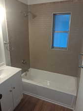 Bathroom with wood finished floors, washtub / shower combination, and vanity
