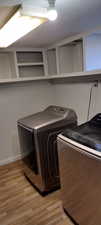 Laundry room with independent washer and dryer and light hardwood / wood-style floors