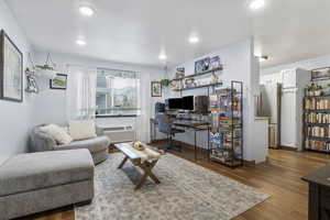 Living room with wood-type flooring and a wall unit AC