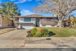 Split foyer home with a garage, a balcony, and a front yard