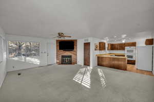 Unfurnished living room featuring sink, a textured ceiling, light colored carpet, and ceiling fan