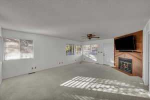 Unfurnished living room with ceiling fan, carpet floors, and a textured ceiling