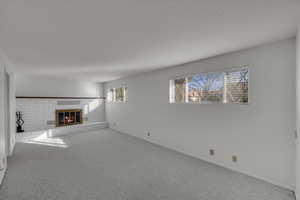 Unfurnished living room featuring a brick fireplace and carpet floors