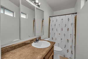 Bathroom featuring a shower with curtain, vanity, and toilet