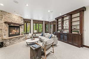 Carpeted living room with a stone fireplace