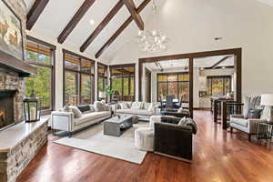 Living room featuring high vaulted ceiling, dark wood-type flooring, a notable chandelier, and a fireplace