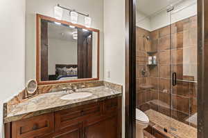 Bathroom featuring toilet, an enclosed shower, and vanity