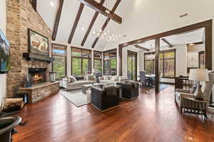 Living room featuring a fireplace, dark hardwood / wood-style floors, high vaulted ceiling, and a notable chandelier