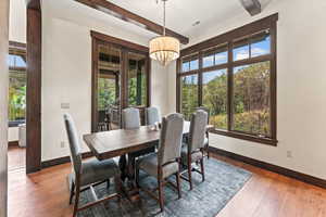 Dining space with a notable chandelier, beamed ceiling, and dark hardwood / wood-style floors