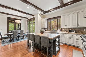 Kitchen featuring a kitchen island, white cabinets, pendant lighting, and a breakfast bar