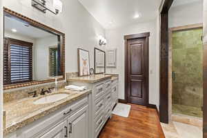 Bathroom featuring hardwood / wood-style floors, walk in shower, and vanity