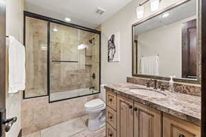 Full bathroom featuring toilet, tile patterned flooring, enclosed tub / shower combo, and vanity