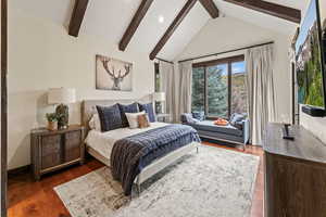 Bedroom featuring high vaulted ceiling, dark wood-type flooring, and beam ceiling