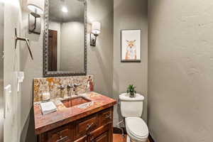 Bathroom featuring vanity, backsplash, and toilet