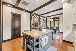 Kitchen with hanging light fixtures, white cabinetry, light stone counters, a fireplace, and a kitchen island