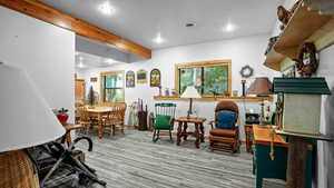 Living area with beamed ceiling, plenty of natural light, and light wood-type flooring