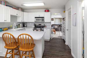 Kitchen with white cabinetry, stainless steel appliances, a breakfast bar, and sink