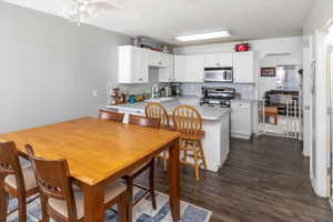 Kitchen featuring a breakfast bar, appliances with stainless steel finishes, dark hardwood / wood-style flooring, kitchen peninsula, and white cabinets